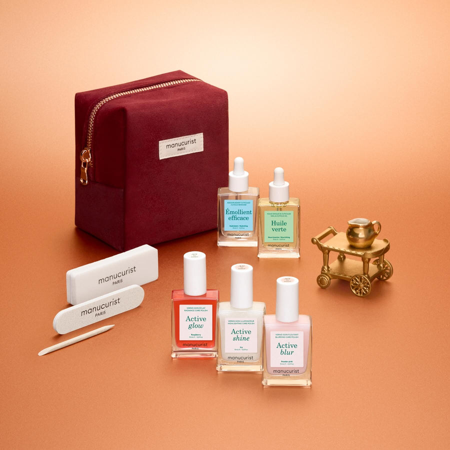 The Manucurist Active™ Starter Kit Gift Set features everything you need to elevate your manicure routine: three nail polishes, two cuticle oils, two nail files, and a wooden cuticle stick, all beautifully packaged in a burgundy velvet pouch and arranged on a soft peach background.