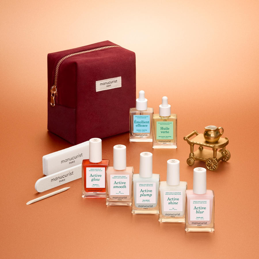The Manucurist Active™ Super Starter Gift Set makes a perfect holiday gift, featuring six nail polish bottles, two cuticle treatments, two nail files, a cuticle pusher, and a burgundy velvet pouch—all beautifully arranged on a peach-colored background to help you achieve beautiful nails as part of your manicure routine.