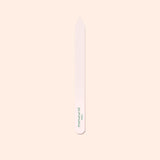 The Manucurist-us Glass Nail File features a pointed tip and "manucurist" in green near the base, shown vertically on a pale beige background.