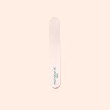A Manucurist-us Glass Polisher with rounded ends rests on a pale surface. “Manucurist-us” is printed vertically in green, making it ideal for gently enhancing the natural shine of your nail plate.