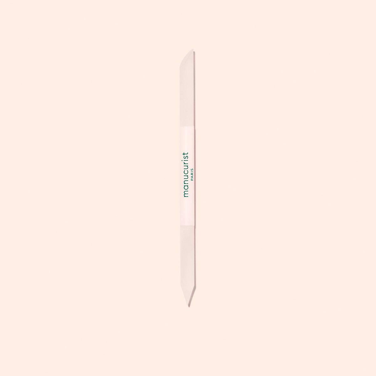 The Manucurist Glass Cuticle Pusher features a pointed tip and beveled edge for precise nail contouring, with "manucurist" in green on a white center section, displayed on a light beige background.