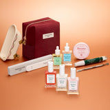 The Manucurist Active™ Ultimate Gift Set, featuring a burgundy pouch, is elegantly displayed on a peach background—surrounded by nail files, a cuticle tool, six nail care bottles, and a round balm tin—making it the perfect upgrade to your manicure routine or a thoughtful holiday gift.
