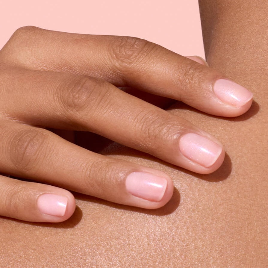 Main aux ongles rose nacré sur dos