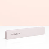 A rectangular gray Manucurist Nail buffer sponge with rounded edges is placed vertically on a light beige background, perfect for smoothing the nail plate and prepping your manicure.