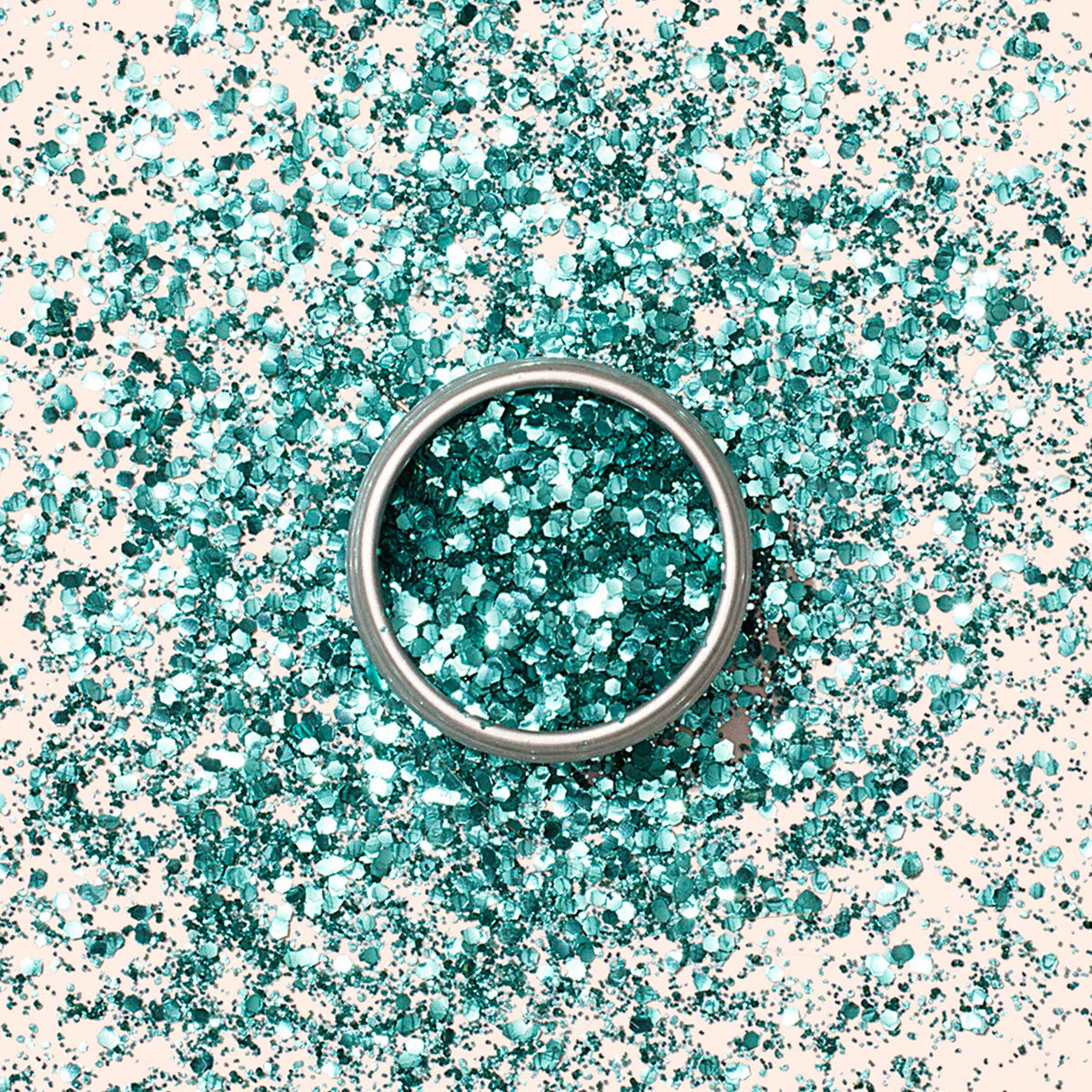 A small round container of Manucurist Turquoise Biodegradable Glitter rests on a plain light beige background, ready to enhance your nail art or gel polish designs.