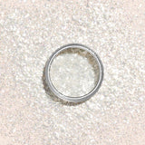 The Manucurist Pearlescent Glitter Flakes come in a small round container on a pale peach background, casting a soft shadow—ideal for adding dazzling shimmer to your next manicure.