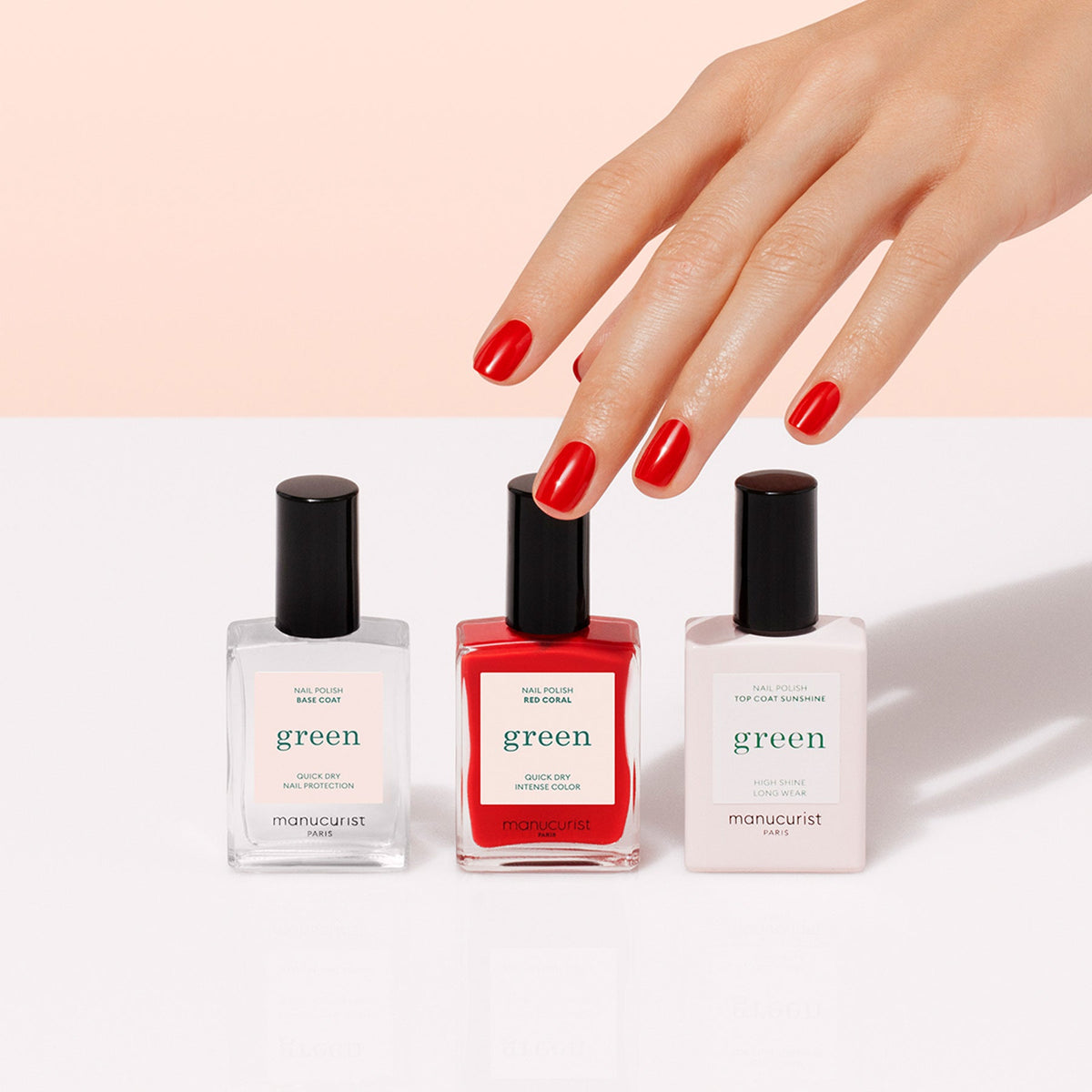 The Manucurist Basic Kit is shown with three bottles side by side on a light beige background. Ideal for gel-effect manicures, the set features a base coat, bright red polish, and top coat—all with sleek black caps.
