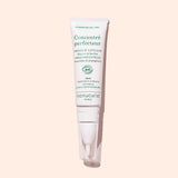 A white tube of Manucurist Nourishing Nail Pen - Cosmos Organic with green text stands upright against a light pink background—ideal for nail and cuticle care.