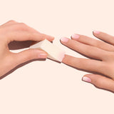 Four white, triangular Manucurist Nail Art Sponges are arranged vertically on a pale background, each casting a soft shadow to the right.