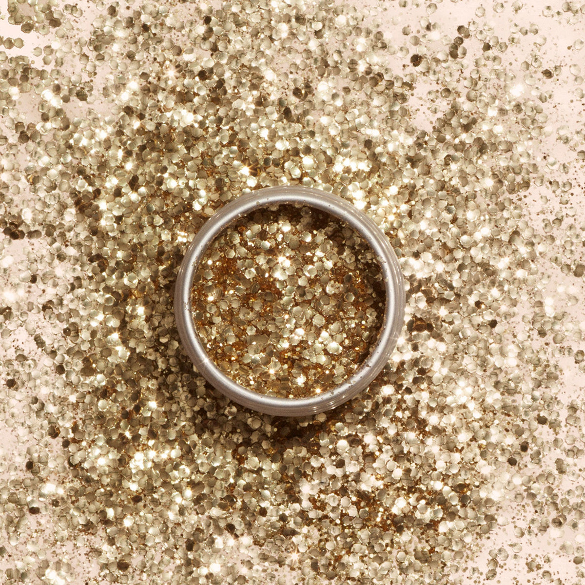 A round tin of Manucurist Gold Biodegradable Glitter rests on a light beige background with a soft shadow—ideal for dazzling nail art or pairing with your favorite gel polish.