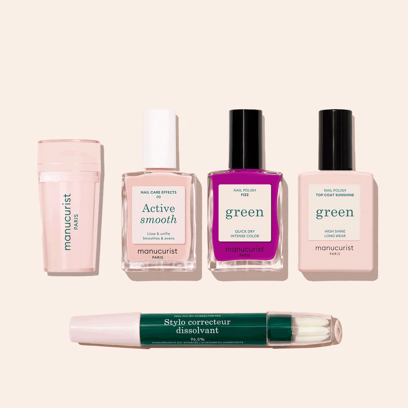 Five manicure products from the Manucurist French Color Kit are shown on a light beige background: a nail buffer, two nude polishes, one bright pink polish, a top coat, and a green corrector pen.