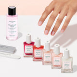 The Manucurist Super Active Manicure Kit features seven essential products—ideal for nail prep and care—including a gray nail file, a white buffer, a pink nail polish remover bottle, and five treatment bottles in shades of pink, red, and clear—all beautifully arranged on a light background to provide everything you need for a flawless manicure.