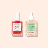Two bottles from Manucurist’s Basic Routine - Sensitive Nails—a vibrant red Active Glow nail polish with a white cap and a clear Serum Complet cuticle serum with a dropper—are beautifully arranged on a light peach background, offering the perfect duo for nail care and moisturized nails.