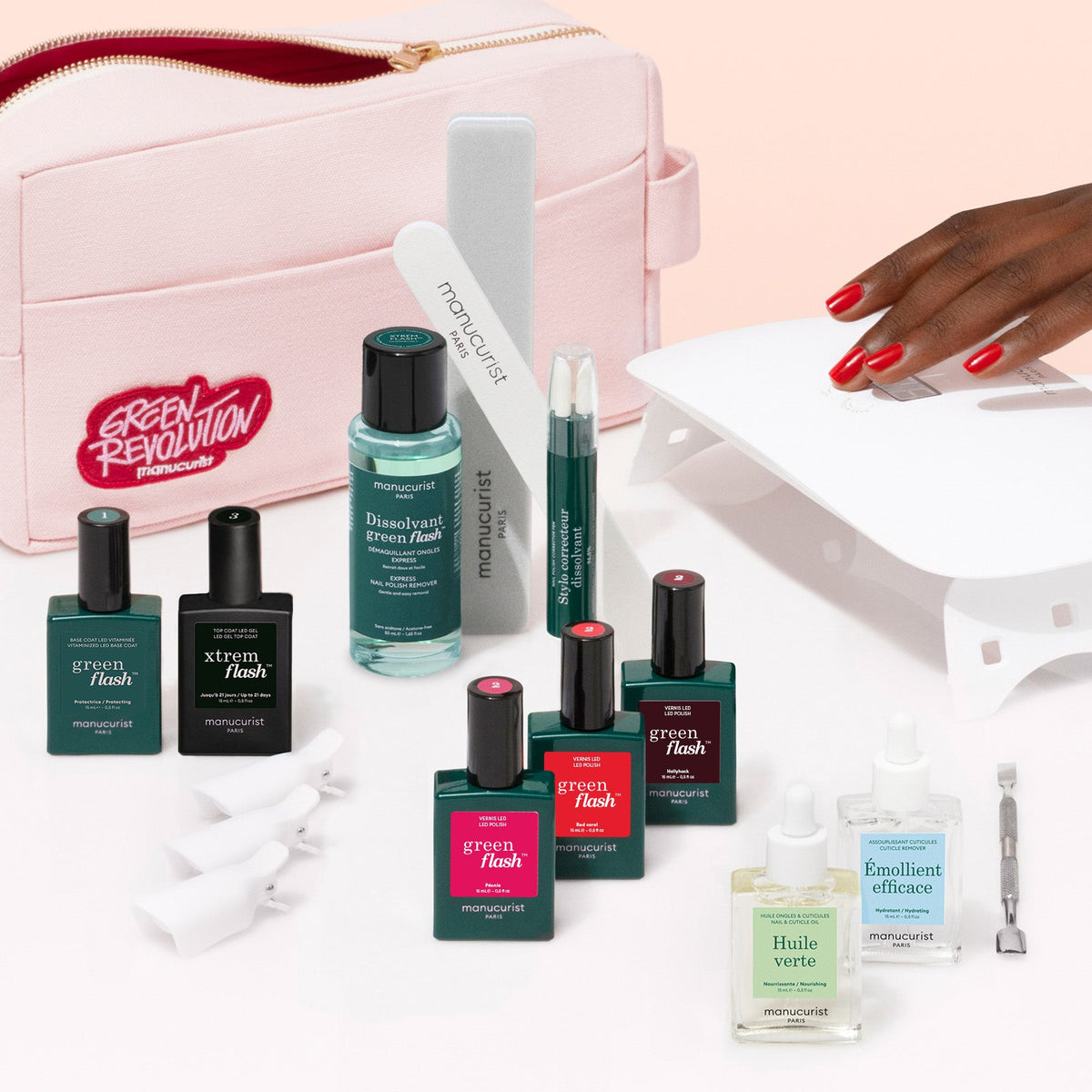 The Manucurist Ultimate Kit features a pink pouch, gel polishes, nail files, a cuticle pusher, LED lamp, remover bottles, and more—everything you need for an ultra-glossy manicure on a light beige background.