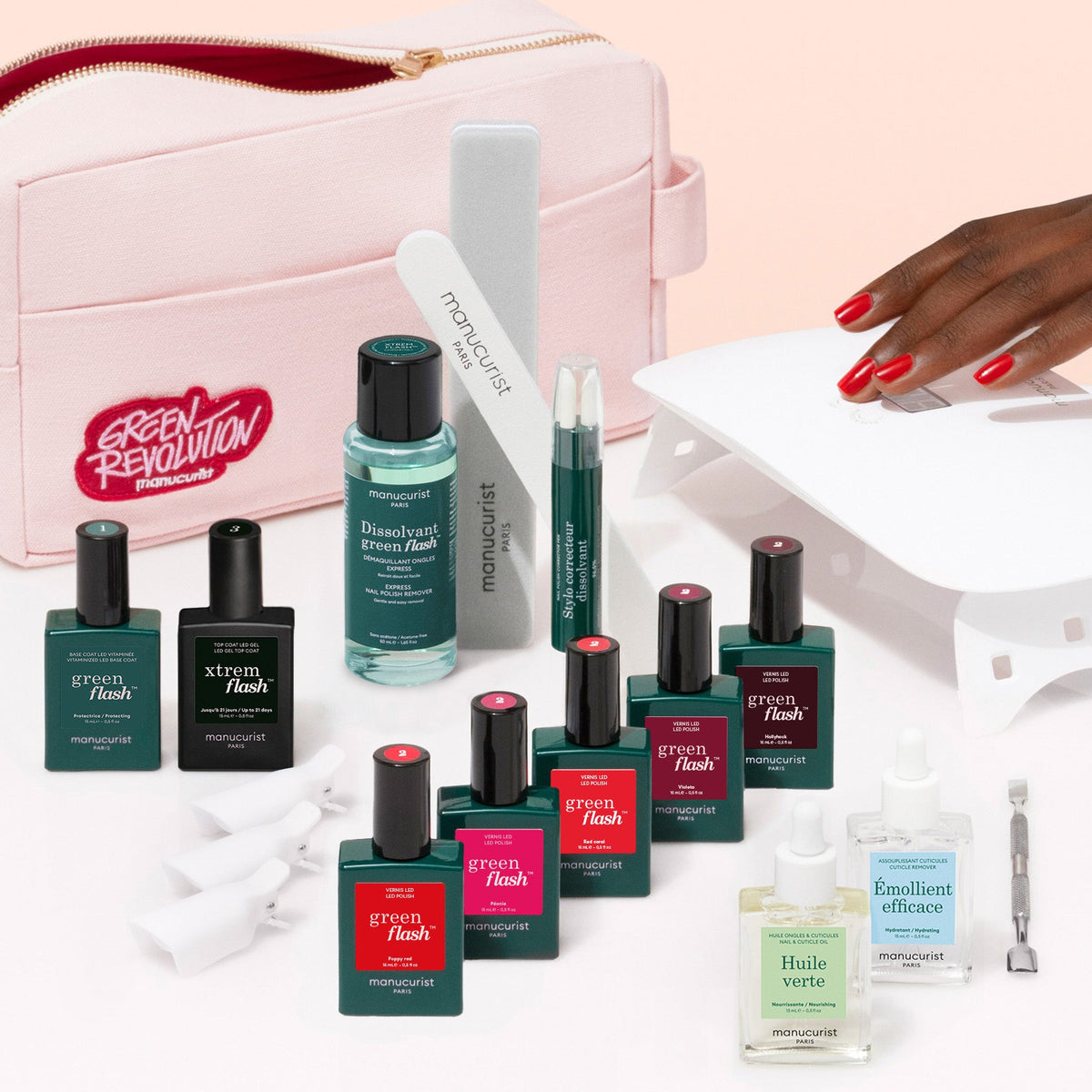 The Manucurist Super Ultimate Kit includes a pink zippered pouch, white UV lamp, 7 Green Flash gel polishes, nail files, cuticle tools, remover bottles, and accessories for an ultra-glossy manicure—all stylishly displayed.