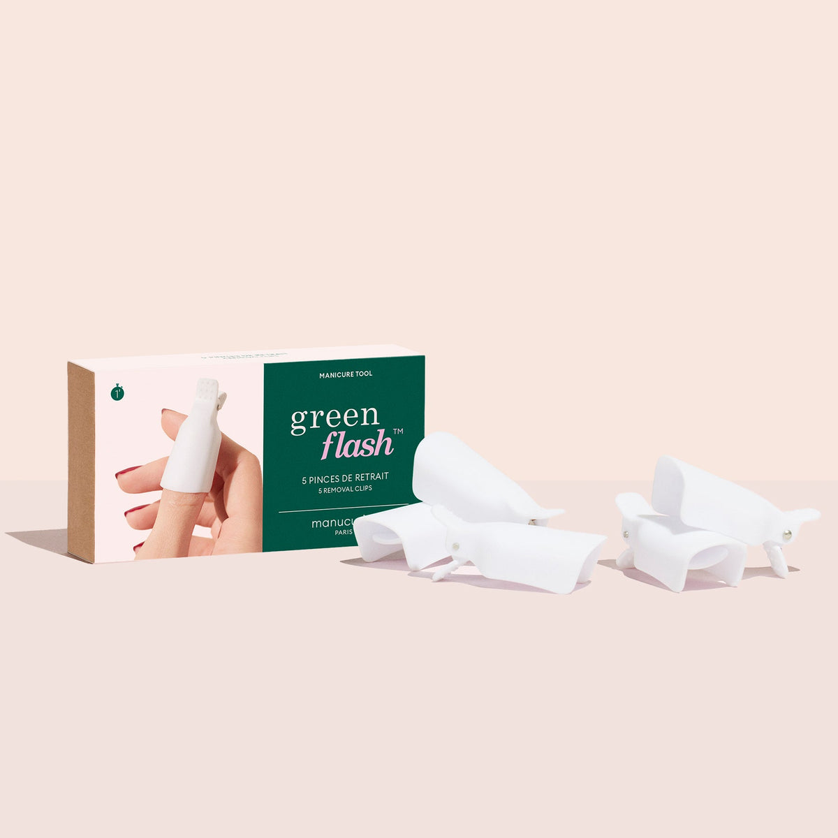 A box of Manucurist-us Green Flash™ Remover Clips is displayed, showing an image of fingers with white clips for gentle nail polish removal and three clips beside the packaging on a light beige background.